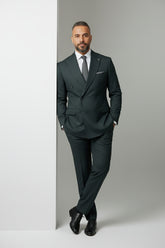 Man in dark green double-breasted suit with peak lapels and slim fit.
